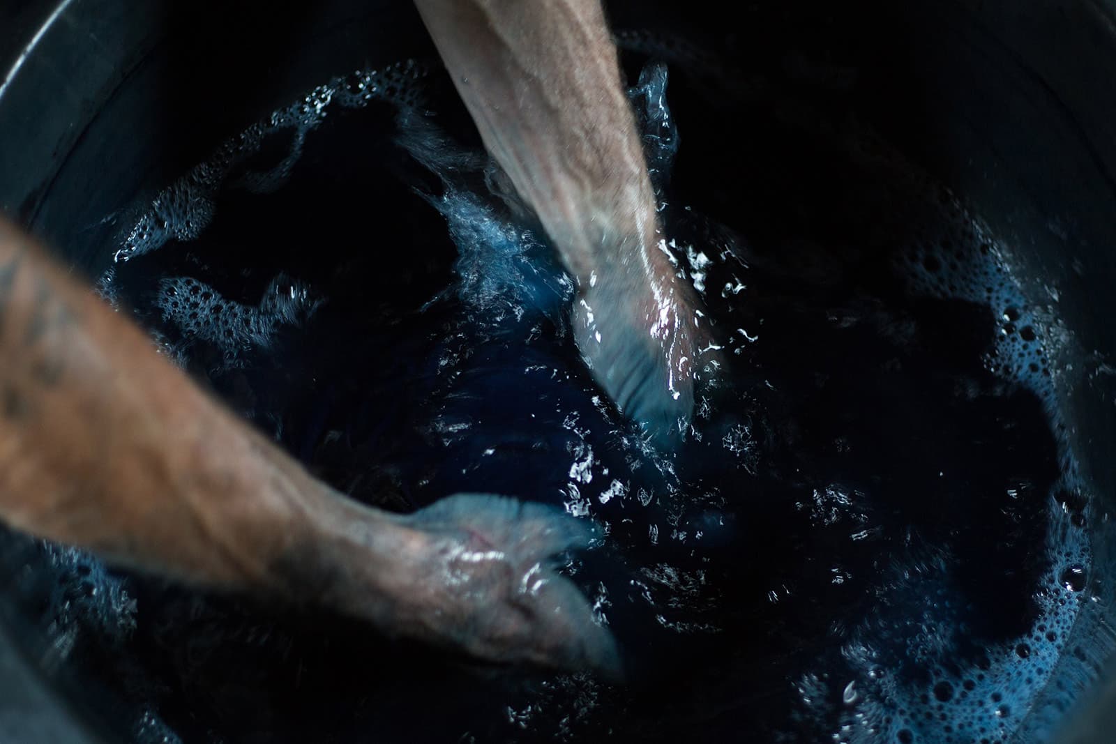 Hands working indigo dye in the Tian Taru studio